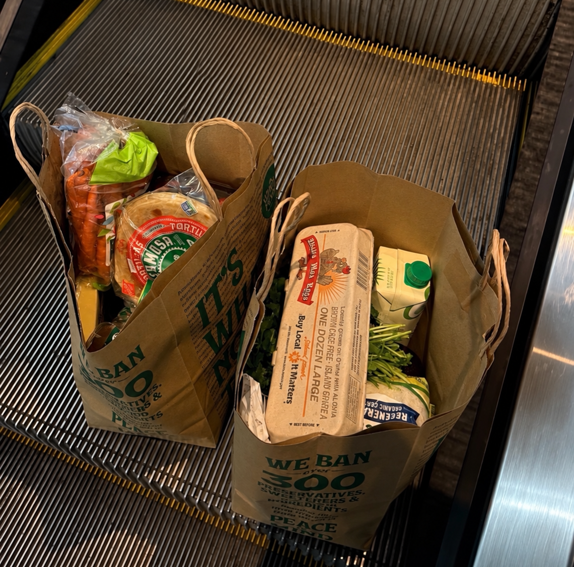 Real grocery bags filled with everyday groceries on a store escalator after a grocery run